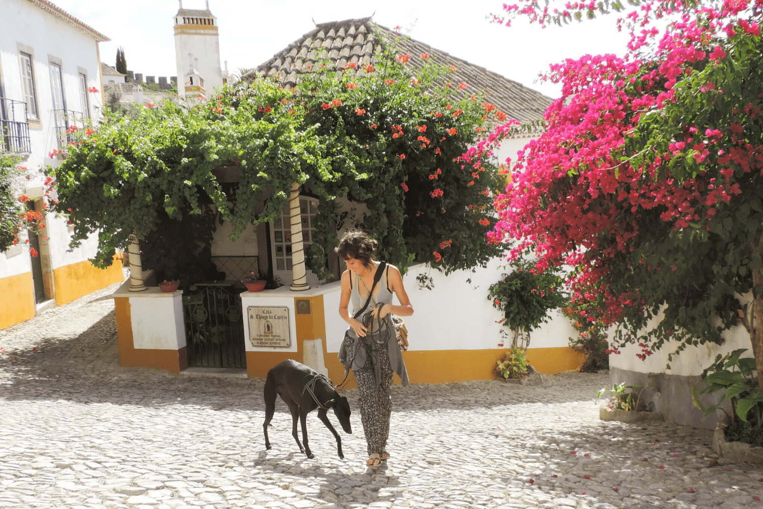 galgo negro y chica paseando en un pueblo de Portugal