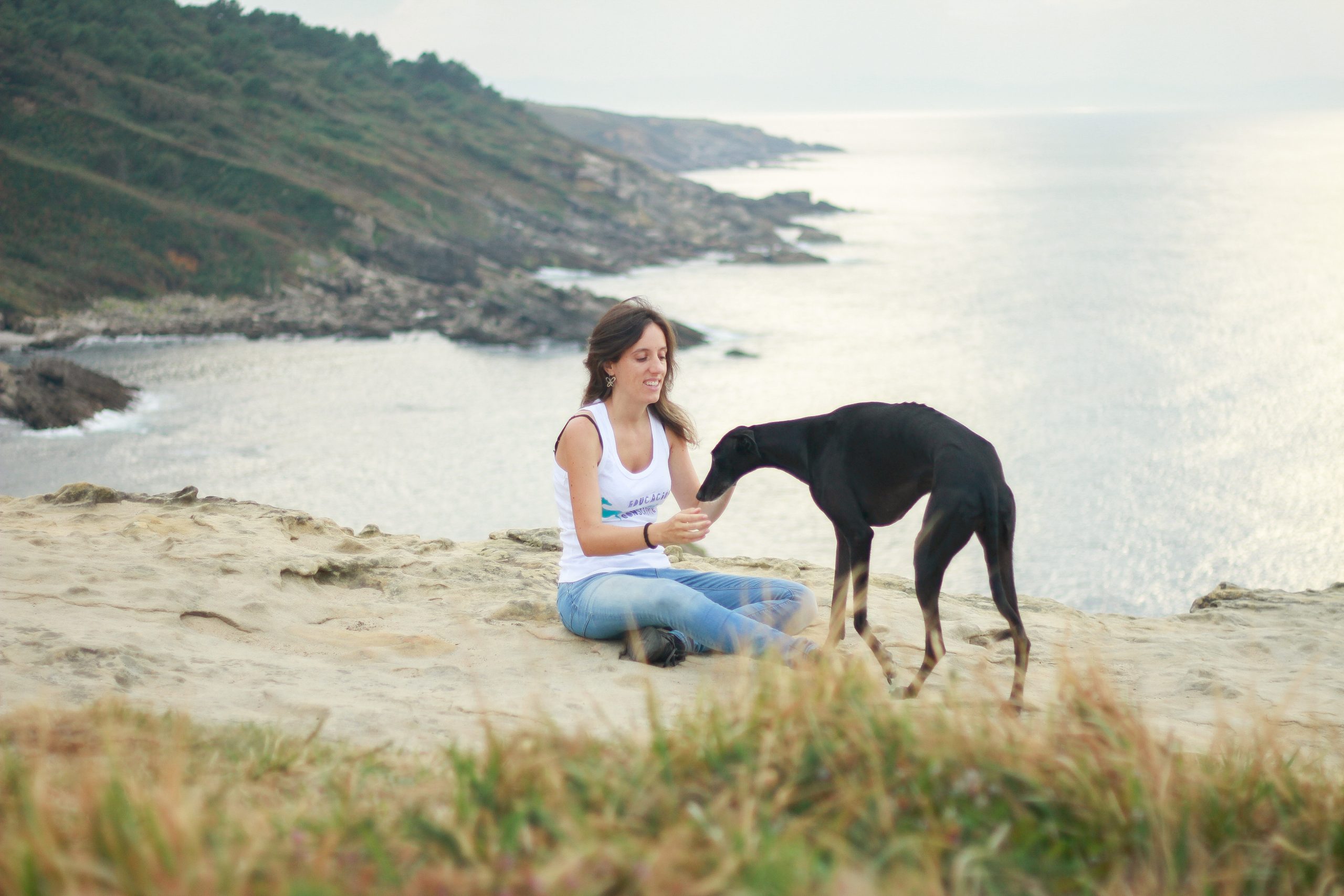 chica y galgo negro en una roca mirando al mar en jaizkibel